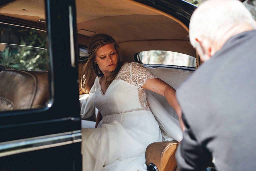 Bride getting into car at wedding